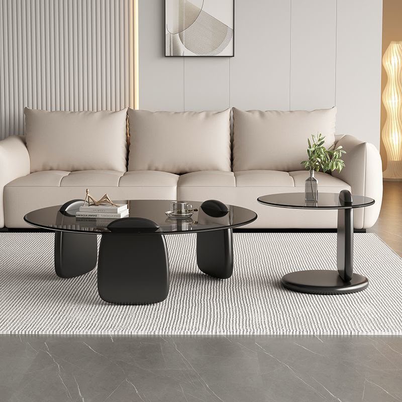Modern round coffee table and side table set featuring smoked tempered glass tops and sculptural black solid wood bases in a contemporary luxury design.2