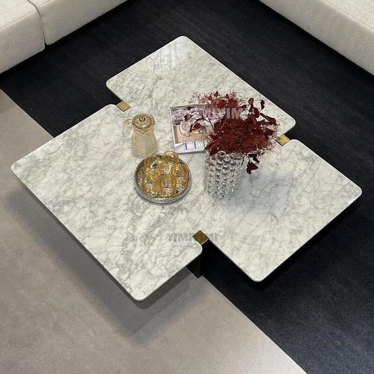 Sereno real marble coffee table with sculptural overlapping tabletop design in a modern luxury living room.